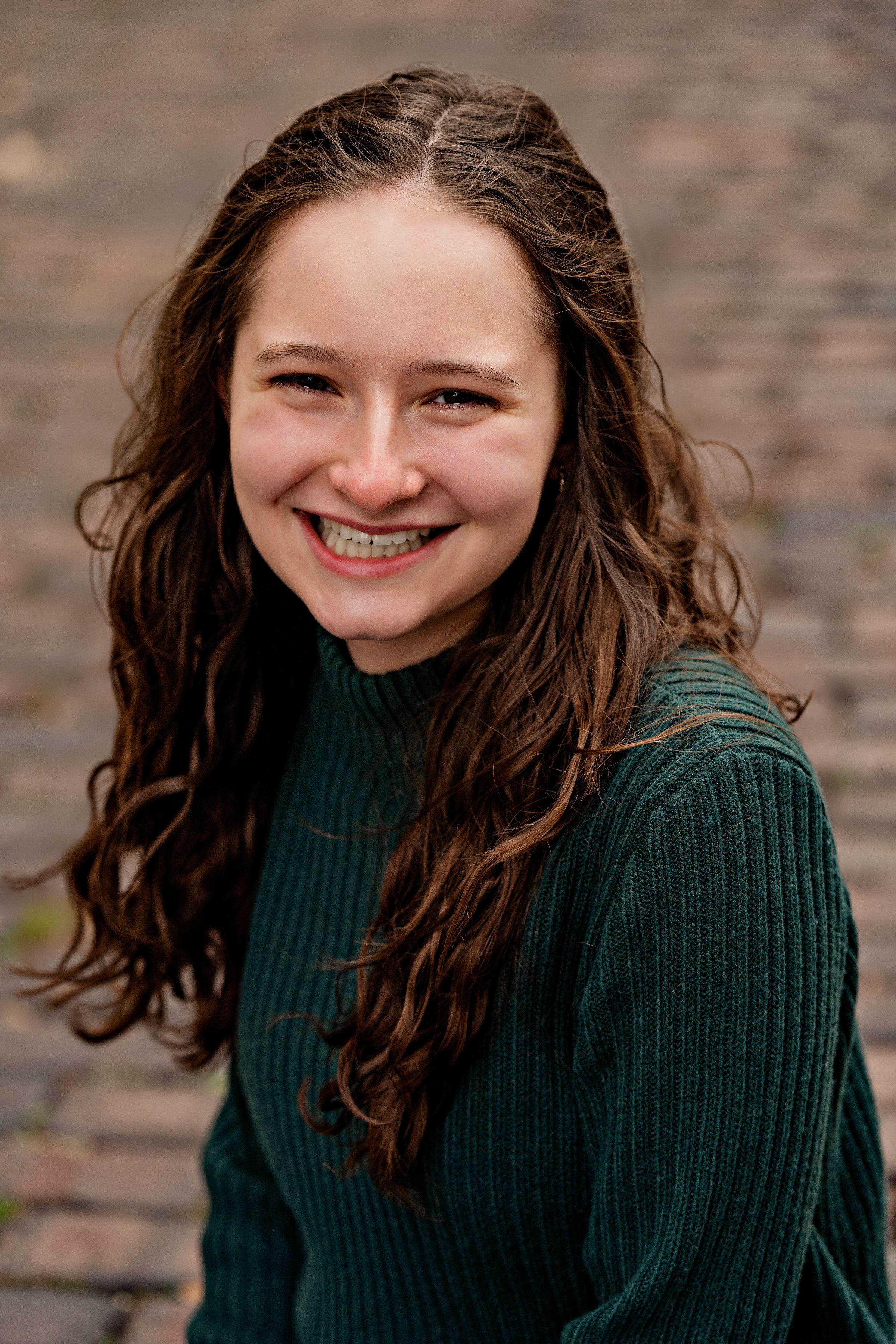 Rose Clubok, a white young woman in a green sweater smiling.